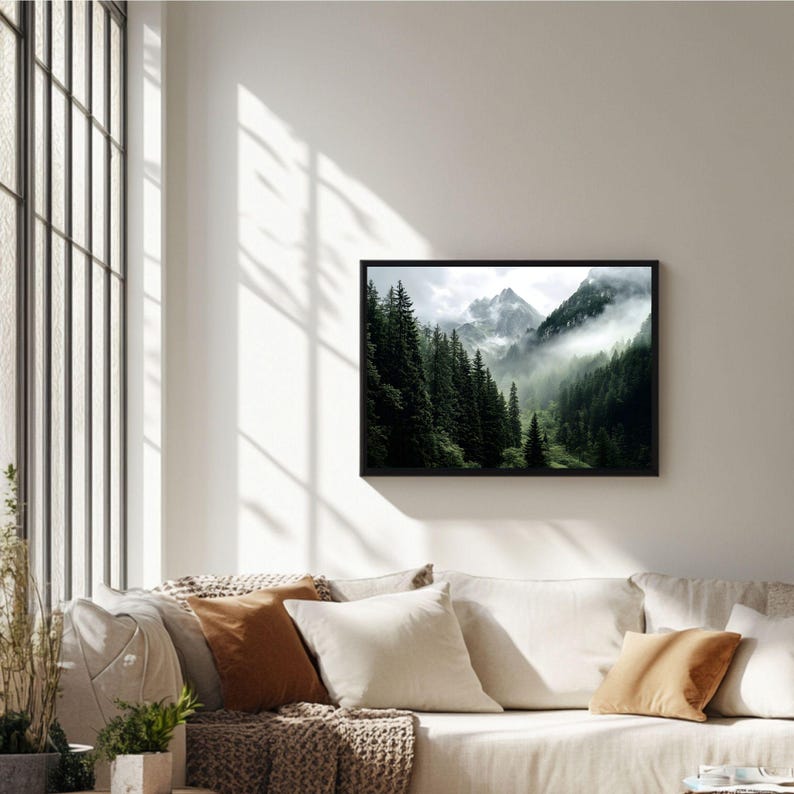 May include: A framed photograph of a mountain range with a misty forest in the foreground. The mountains are covered in snow and the forest is lush and green.