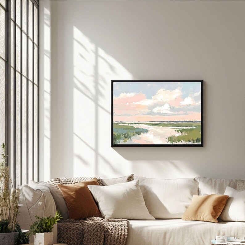 May include: A framed painting of a landscape with a river flowing through a field of green grass. The sky is a soft pink and blue with fluffy white clouds.