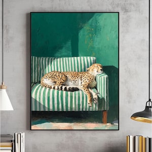 May include: A framed art print depicts a cheetah resting on a green and white striped sofa. The cheetah has a tan coat with black spots. The background is a solid green wall with a shadow.