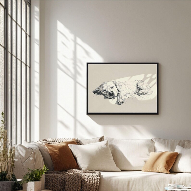 May include: A framed black and white art print depicting a sleeping dog. The dog is shown lying down, with its eyes closed, and is lit by a beam of light. The artwork is displayed above a sofa with several cushions.