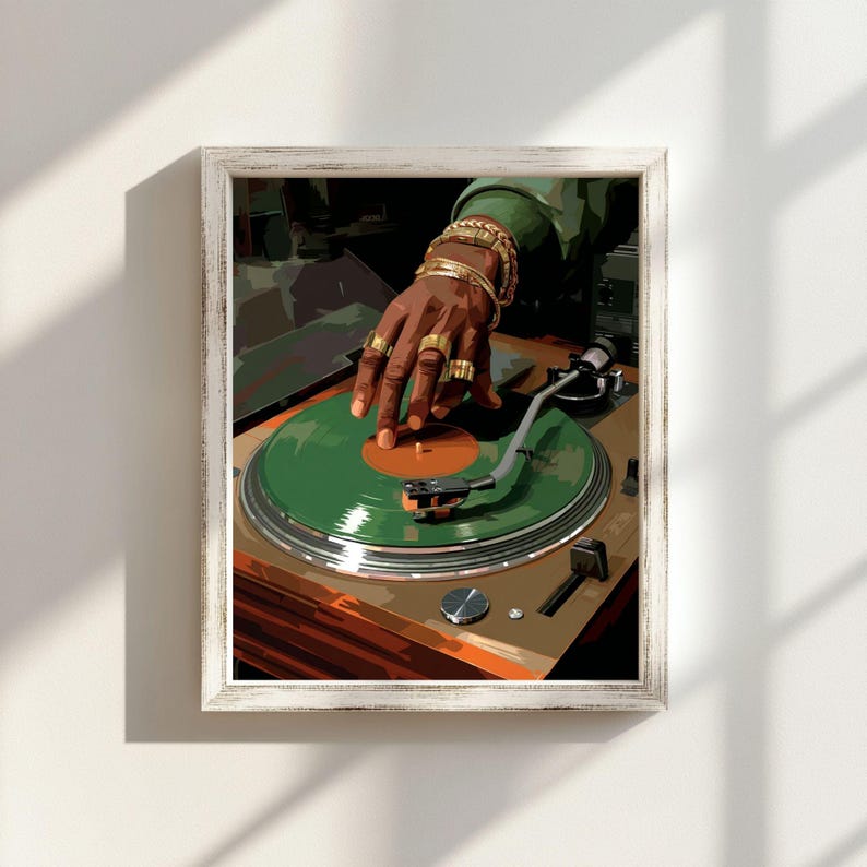 May include: Framed artwork featuring a DJ's hand adorned with gold rings and bracelets, manipulating a green vinyl record on a turntable. The artwork has a vintage aesthetic, with a wooden frame and a warm color palette.