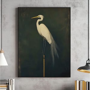 May include: A white egret with a long, slender neck and a long, pointed beak stands on a gold pole against a dark green background.