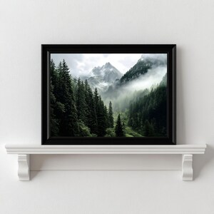 May include: A framed photograph of a misty mountain landscape with lush green trees in the foreground. The mountains are covered in clouds and fog, creating a sense of mystery and tranquility.