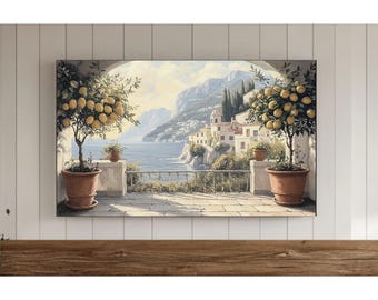Op de afbeelding: Een ingelijste canvas print met een schilderachtig Italiaans kustlandschap. Het kunstwerk toont een terras met citroenbomen in potten, een stenen balustrade en een ver dorp langs de kustlijn. De lucht is zachtblauw met pluizige wolken.