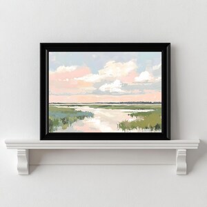 May include: A framed painting of a landscape with a river flowing through a field of green grass. The sky is a soft blue with pink clouds.
