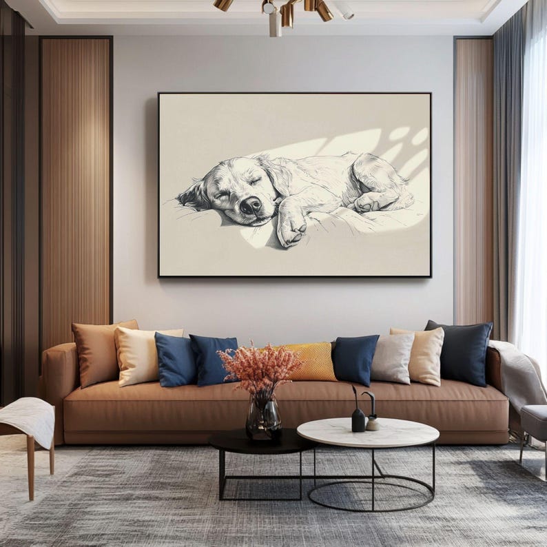 May include: A monochrome sketch of a sleeping dog in a black frame. The artwork hangs above a brown sofa with cushions. A coffee table and rug are in front of the sofa. The room has neutral tones and natural light.