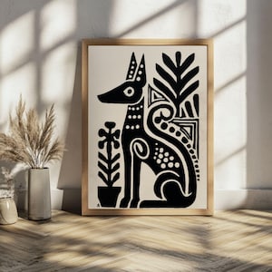 May include: Black and white art print featuring a stylized dog with decorative patterns and plant motifs. The artwork is framed in a light wood frame and set against a neutral background. The print's design is reminiscent of folk art.