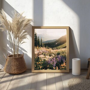 May include: A framed photograph of a mountain meadow with wildflowers in shades of purple, pink, and yellow. The meadow is in the foreground, with a mountain range in the background.