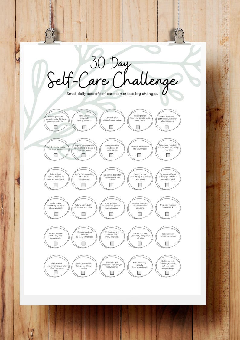 May include: A white 30-Day Self-Care Challenge poster, held by a silver clip. The poster features a floral design and daily self-care activities. The text reads "Small daily acts of self-care can create big changes."
