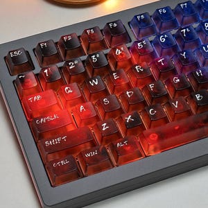 May include: A backlit mechanical keyboard with transparent keycaps. The keys transition from red to blue, with white lettering. The keyboard has a dark gray frame and is angled slightly upwards.