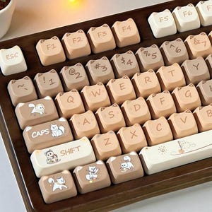 May include: A custom mechanical keyboard with cat-shaped keycaps in shades of beige and brown. The keycaps feature cat illustrations and standard keyboard symbols. The keyboard is set in a wooden frame, offering a unique and playful aesthetic.
