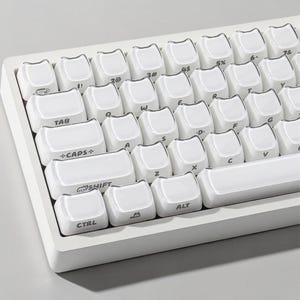May include: A white mechanical keyboard with white keycaps. The keycaps have black lettering and symbols. The keyboard includes keys such as "TAB", "CAPS+", "SHIFT", "CTRL", and "ALT". The keyboard is designed for computer use.