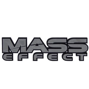 May include: A silver 3D logo for the video game Mass Effect. The logo is made up of the words "Mass Effect" in a bold, sans-serif font.
