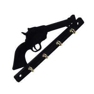 K&ouml;nnte beinhalten: Schwarzer Schl&uuml;sselhalter aus Metall in Form eines Revolvers mit vier goldenen Haken.