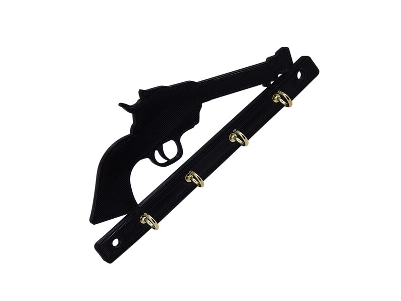 K&ouml;nnte beinhalten: Schwarzer Schl&uuml;sselhalter aus Metall in Form eines Revolvers mit vier goldenen Haken.