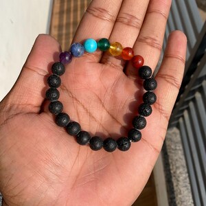 May include: A black lava rock bracelet with seven chakra beads. The beads are purple, blue, turquoise, green, yellow, orange, and red.