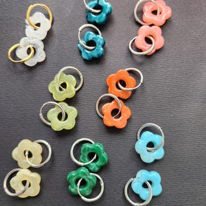 Peut inclure: Un ensemble de 10 paires de boucles d'oreilles créoles en forme de fleur. Les boucles d'oreilles sont en argent et sont disponibles dans une variété de couleurs, notamment le vert, le bleu, le jaune et le rose.