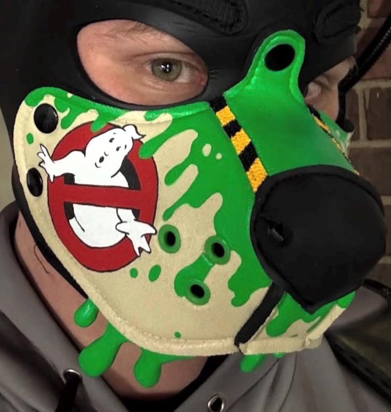 Peut inclure: Une cagoule noire avec un museau vert et beige orn&eacute; du logo Ghostbusters. Le museau pr&eacute;sente un fant&ocirc;me blanc dans un cercle rouge barr&eacute;, agr&eacute;ment&eacute; de motifs de slime vert et de bandes de signalisation noires et jaunes sur le dessus.