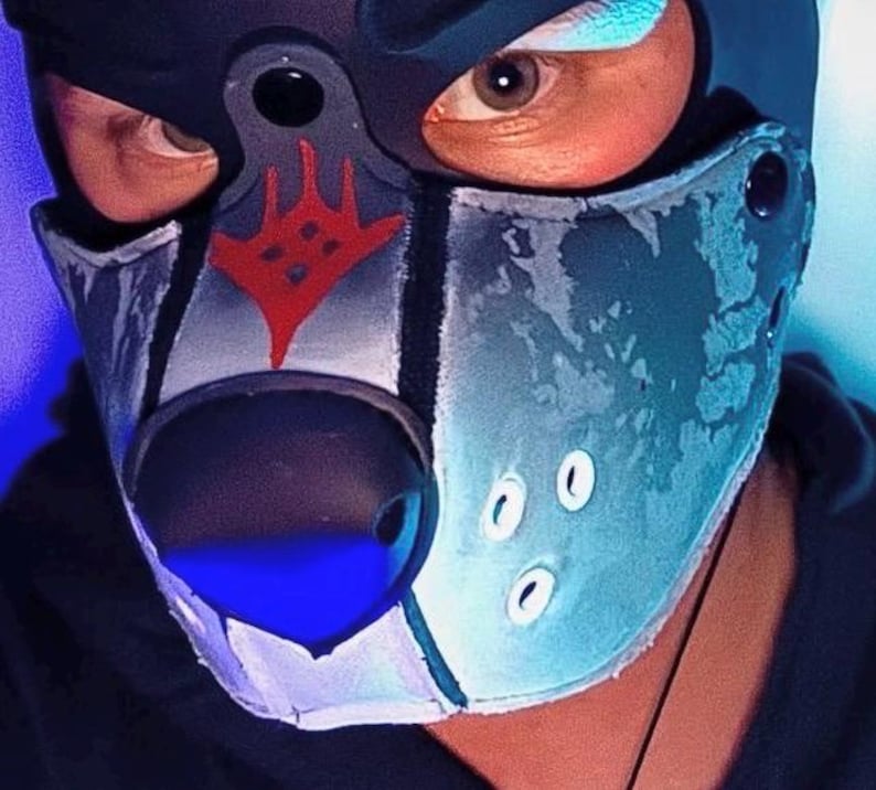 Peut inclure: Un masque cagoule inspir&eacute; d'un animal, noir et bleu, dot&eacute; d'un nez noir pro&eacute;minent, d'un symbole graphique rouge sur le front et de trois petits accents circulaires blancs sur le c&ocirc;t&eacute;. Le masque pr&eacute;sente une finition textur&eacute;e et des bordures noires.