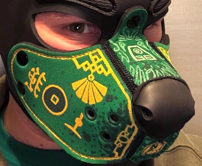 Peut inclure: Un masque museau de style animal vert et noir avec des motifs imprim&eacute;s jaunes, notamment un &eacute;ventail, une pi&egrave;ce circulaire et des formes g&eacute;om&eacute;triques. Le masque poss&egrave;de un nez noir, des &oelig;illets d'a&eacute;ration noirs et des rivets noirs.
