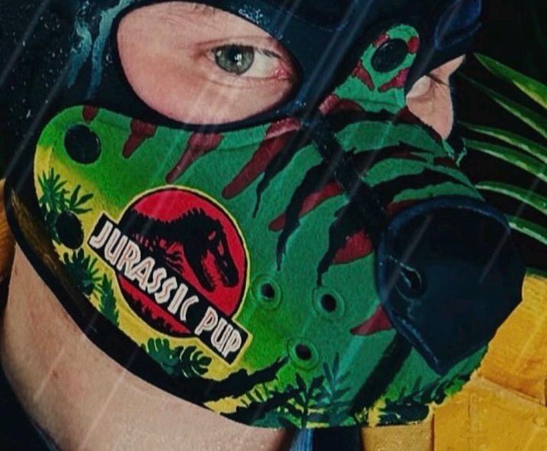 Peut inclure: Une cagoule noire avec une pi&egrave;ce de museau &agrave; motifs verts et rouges arborant un logo circulaire avec une silhouette de dinosaure noire et le texte JURASSIC PUP. Le museau pr&eacute;sente des accents noirs, des trous d'a&eacute;ration et un nez noir.
