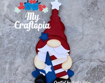May include: A patriotic gnome figure with a red hat, white beard, and blue and white accents. The gnome holds a blue and white star-spangled banner. The text "My Craftopia" is above the gnome, and "Created by Leslie Foley" is below.