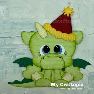 May include: A green paper dragon with large blue eyes, wearing a red party hat with a yellow star. The dragon has green wings and is sitting down. The text "My Craftopia" is at the bottom of the image.
