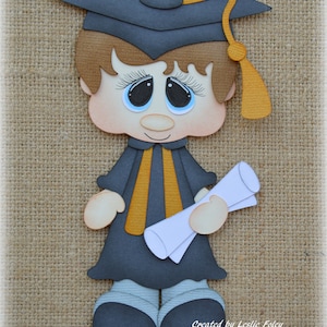 Puede incluir: Una figura de graduación de papel de una persona que lleva una gorra y una bata negras con una borla dorada, sosteniendo un rollo de diploma blanco. La figura tiene el pelo castaño, una tez clara y ojos azules.