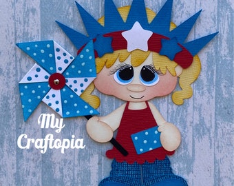 May include: A paper craft of a girl wearing a red, white, and blue crown holding a blue and white pinwheel. The text "My Craftopia" is in the lower left corner of the image. The text "created by Leslie Foley" is in the lower right corner of the image.