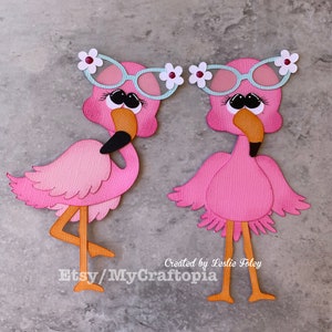 May include: Two pink flamingo cutouts with sunglasses and flower accents. The flamingos have orange beaks and legs, and black eyes. The text "Created by Leslie Foley" and "Etsy/MyCraftopia" is visible.
