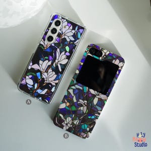 May include: Two phone cases with a stained glass floral design. The case on the left has a clear back and the case on the right has a black back. Both cases feature a purple, blue, and green floral pattern.