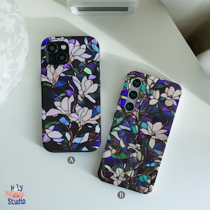 May include: Two phone cases with a stained glass floral design. The cases feature white magnolia flowers against a backdrop of blue, purple, and green hues. The cases are labeled A and B.