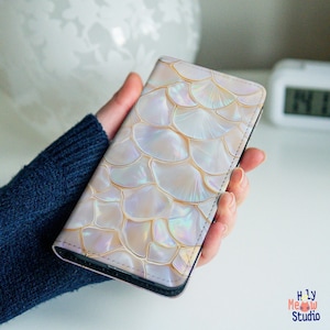 May include: A white phone case with a pearlescent iridescent pattern. The case has a textured surface and a subtle shimmer.
