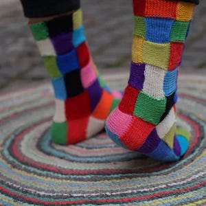May include: A pair of colorful socks with a patchwork design. The socks are made of a soft, knitted fabric and feature a variety of bright colors, including red, blue, green, yellow, and purple.