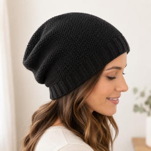 May include: A solid black beanie with a textured knit pattern and a ribbed cuff. The hat features a slouchy silhouette that sits comfortably on the head, showcasing a consistent dark color and a detailed, woven fabric construction throughout.