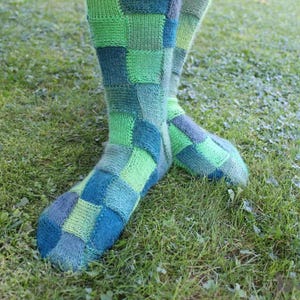 May include: A pair of colorful socks with a patchwork design in shades of green and blue. The socks are made of a soft, knitted fabric and have a comfortable fit.