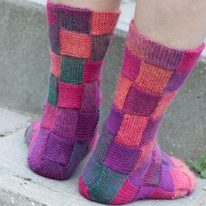 May include: A pair of colorful knitted socks with a patchwork design in shades of pink, purple, green, and orange.