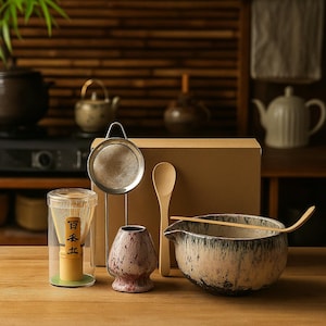May include: A Japanese tea ceremony set featuring a ceramic bowl, bamboo whisk, strainer, scoop, and a small ceramic cup. The bowl has a speckled glaze, and the whisk is in a clear container. The set is arranged on a wooden surface.