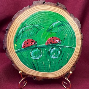 Arte mural de rebanadas de madera pintadas a mano: Mariquitas sobre hierba mojada con sombrillas. Ilustración de naturaleza encantadora. Decoración rústica redonda de 18 cm.