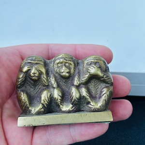 May include: Three brass monkeys, each covering a different sense: see no evil, hear no evil, speak no evil. The monkeys are sitting on a small, rectangular base.