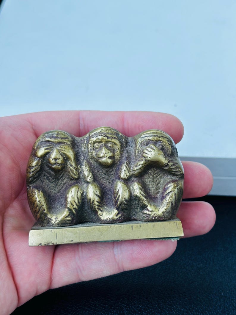 May include: Three brass monkeys, each covering a different sense: see no evil, hear no evil, speak no evil. The monkeys are sitting on a small, rectangular base.