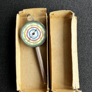May include: A silver-coloured measuring tool with a circular dial and a long handle. The dial has a green, blue, and red colour scheme and numbers ranging from 50 to 400. The tool is in a cardboard box.