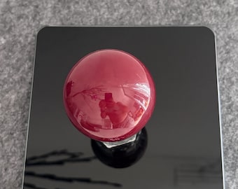 May include: A shiny, round, deep red object sits on a black digital scale, displaying a weight of 201. The scale has a digital display and the brand name "Yilai". The object reflects the surrounding environment.