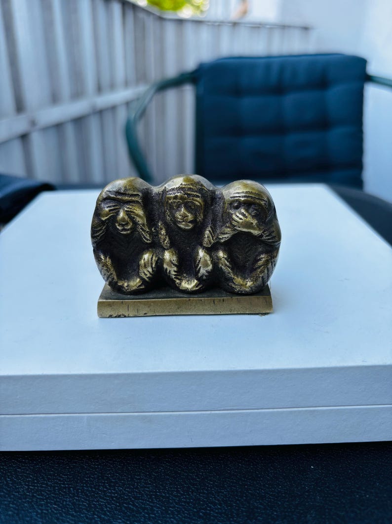 May include: Three brass monkeys, each covering a different sense: see no evil, hear no evil, speak no evil. The monkeys are sitting on a small, rectangular base.