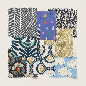 May include: Assortment of fabric swatches featuring various patterns and colors, including a blue and white floral design, a gold and white geometric pattern, a blue and white chevron pattern, a blue and white rain drop pattern, a gold and white leaf pattern, a black and white chevron pattern, a black and white floral pattern, and a blue and white cloud pattern.
