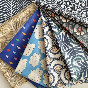 May include: A collection of eight fabric swatches featuring various patterns in shades of blue, brown, and white. The patterns include geometric shapes, leaves, clouds, and raindrops.