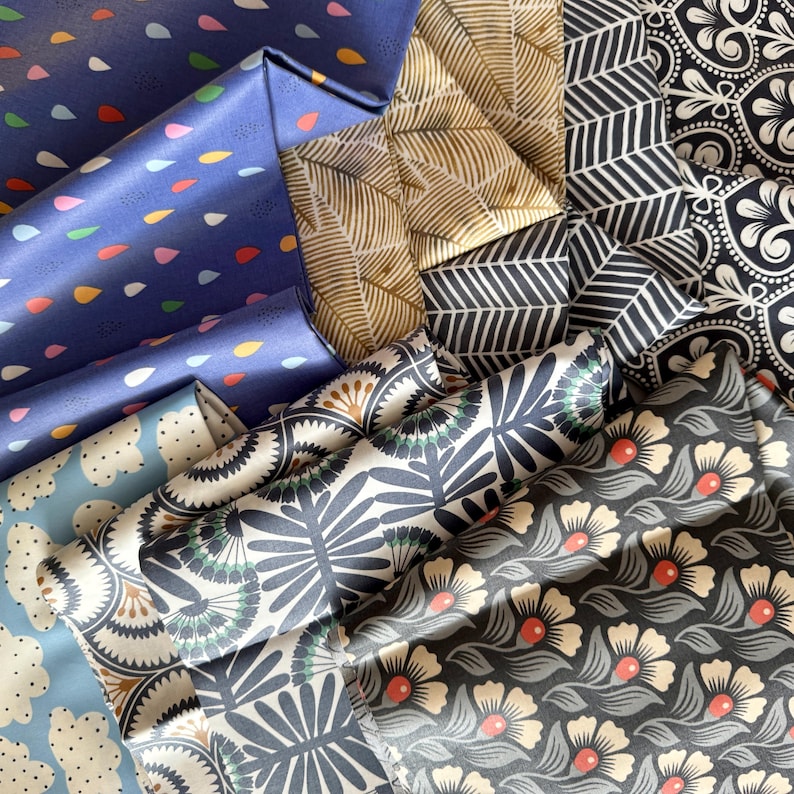 May include: A collection of fabric swatches in various patterns and colors, including blue, black, white, and gold. The fabrics feature geometric, floral, and abstract designs.