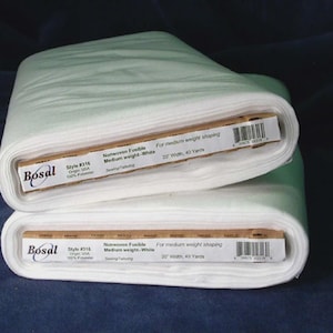 Peut inclure: Deux rouleaux de tissu d'entoilage thermocollant blanc Bosal. Chaque rouleau est étiqueté avec des détails, y compris le numéro de style, l'origine et les dimensions de 50.8 cm de large et 36.6 mètres de long. Le tissu est de poids moyen.