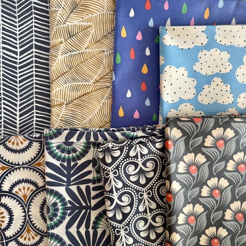 May include: Assortment of fabric swatches in various patterns and colors, including a blue fabric with raindrops, a blue fabric with white clouds, a beige fabric with a leaf pattern, a black and white fabric with a geometric pattern, a black and white fabric with a floral pattern, and a black and white fabric with a heart pattern.