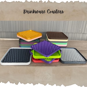 May include: A set of drinkware coasters in various colors, including gray, purple, green, red, yellow, brown, and beige. The coasters are made of a textured material and have a honeycomb pattern. The coasters are stacked on top of each other, and the text "Drinkware Coasters" is visible at the top of the image.